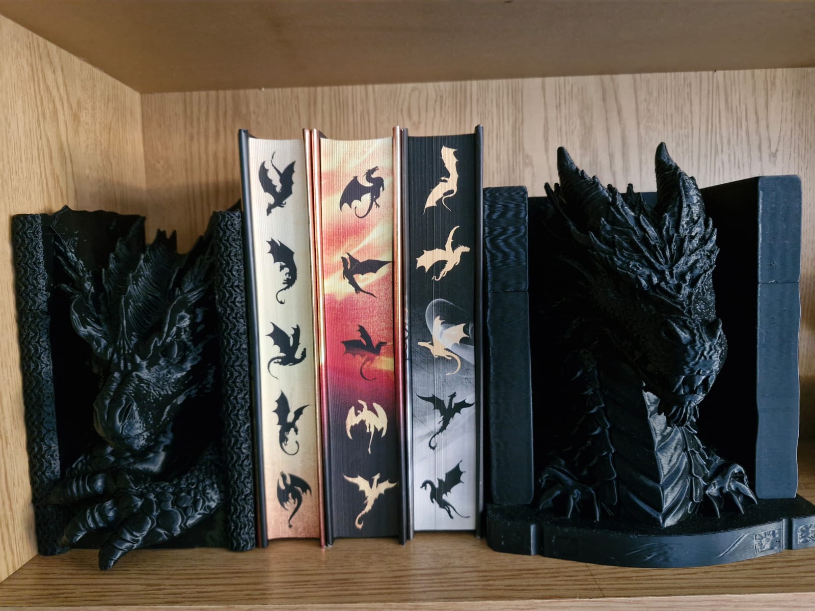 A pair of black dragon bookends holding a row of books